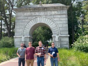 Students stand in front of a stone arch