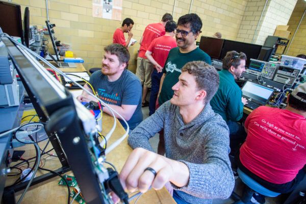 Students engaged in teamwork at a computer in a power electrics lab, demonstrating collaboration in a technical environment.